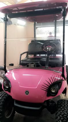 a pink golf cart with fake eyelashes on it