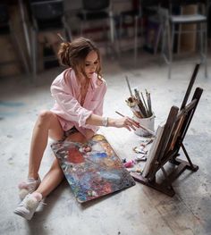 a woman is sitting on the floor painting