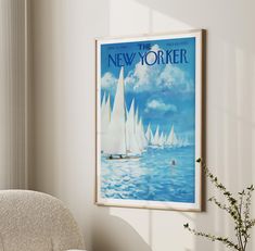 a poster hangs on the wall next to a chair and vase with flowers in it