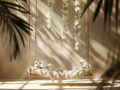 a swing with flowers hanging from it next to a palm tree and a plant in the background