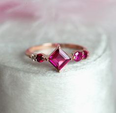 a pink tourmaline ring sitting on top of a white surface