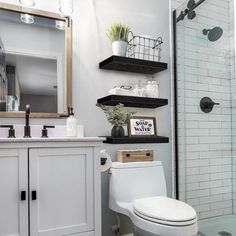 a white toilet sitting in a bathroom next to a walk in shower under a mirror