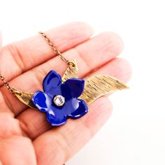 Beautiful variable length necklace is featuring blue enamel flower, brass leaves, Swarovski crystal and antique polished brass chain. Flower, brass leaves and clear Swarovski crystal are layered to form eye catchy focal floral component, and then it is attached to chains with a long extender, making it easy to wear at different lengths. Hand cut copper flower with torch fired glass enamel in royal blue color Hand cut brass leaves Antique polished brass chain with lobster clasp & 4 in extende Royal Blue Flowers, Leaves Necklace, Unique Jewelry Gifts, Length Necklace, Fire Glass, Royal Blue Color, Enamel Flower, Leaf Necklace, Brass Chain