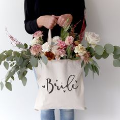 a person holding a bag with flowers and greenery in it that says miss to mrs