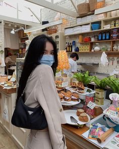 a woman wearing a face mask standing in front of a counter