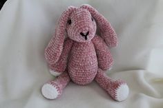 a pink crocheted bunny sitting on top of a white sheet