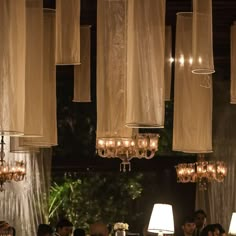 several chandeliers hanging from the ceiling above a table with people sitting at it