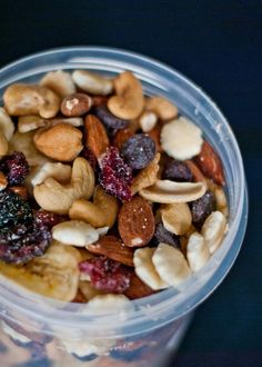 a plastic container filled with nuts and raisins on top of a black table