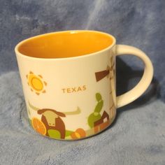 a close up of a coffee cup on a blue blanket with the word texas printed on it