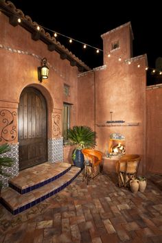 an outdoor patio with lights strung from the ceiling and potted plants on the steps