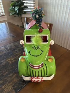 a green toy car sitting on top of a wooden table next to a christmas tree