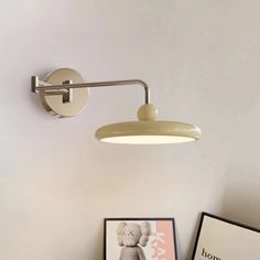 a white wall mounted light on the side of a wall next to a framed photograph