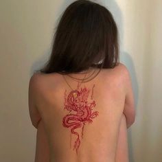 the back of a woman's body with a dragon tattoo on her left side