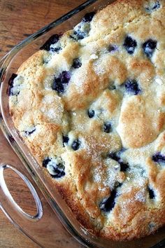 a blueberry cobbler in a glass casserole dish on a wooden table