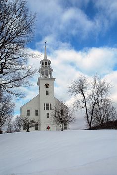 a white church with a steeple in the snow