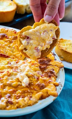 a person is dipping some food into a pizza crust with cheese and other toppings