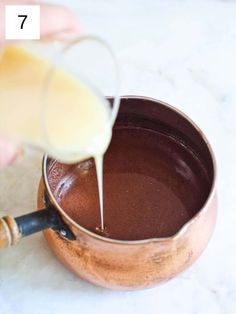 a person pouring liquid into a pot filled with chocolate