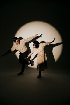 two people standing in front of a full moon with their arms out and hands outstretched