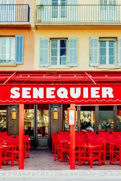 the outside of a restaurant with red tables and chairs