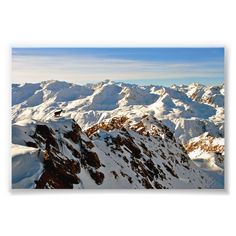 a snowboarder is flying over the top of a snowy mountain range with mountains in the background