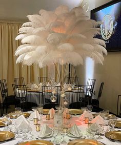 the centerpiece is decorated with white feathers and gold plates