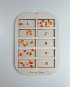 a wooden board with candy in it and numbers on the side, as well as orange candies