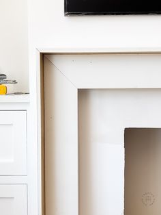 a white fireplace with a black tv above it and a yellow fire hydrant in the corner