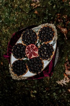 a white plate topped with cookies covered in blackberries and pomegranates