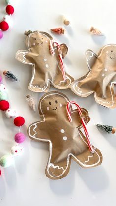 three gingerbread cookies with candy canes and candies scattered around them on a white surface