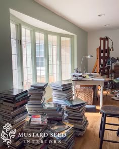 a pile of books sitting on top of a hard wood floor next to a window