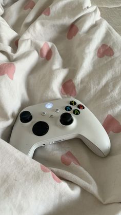 a white controller sitting on top of a bed covered in pink polka dot sheets,