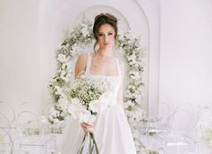 a woman in a white dress holding a bouquet of flowers