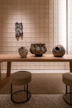 a table with two vases sitting on top of it in front of a wall