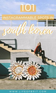 a woman sitting on the steps in front of a building with a large sunflower