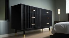 a black dresser with gold handles in a bedroom