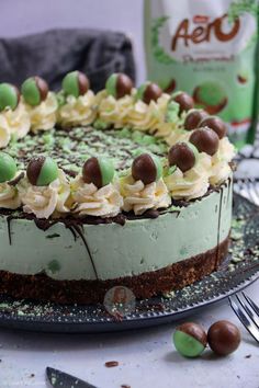 a cake with white frosting, chocolate and green candy on it next to a bag of aeno milk