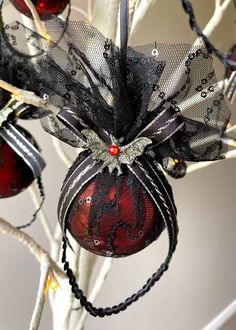 an ornament hanging from a tree decorated with black mesh and red glass ornaments