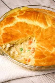 a chicken pot pie in a glass dish with a piece missing from it's crust