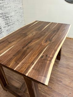 a wooden table sitting on top of a hard wood floor next to a brick wall