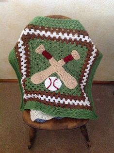 a crocheted blanket with baseballs and bats on it sitting in a chair