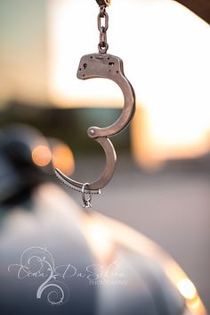 a close up of a metal object hanging from a chain on a car's hood