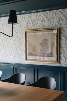 a table with chairs in front of a painting hanging on the wall next to it