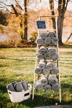 a ladder with towels stacked on top of it in the grass next to a basket