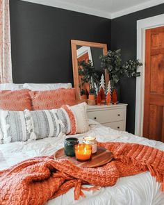 an orange blanket is on the bed next to a candle and some potted plants