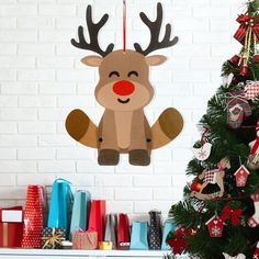 a christmas tree decorated with paper reindeers and presents in front of a white brick wall