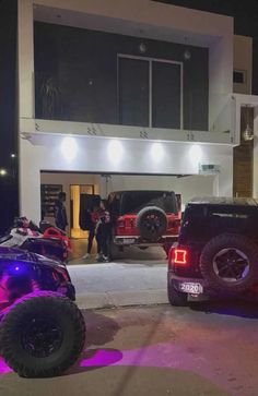 two vehicles parked in front of a building with people standing outside the building at night