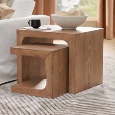 a wooden table with a bowl on top of it next to a couch and window