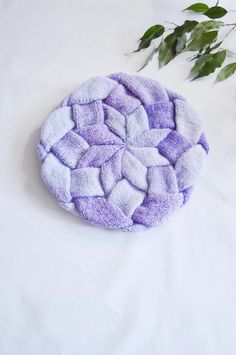 a purple and white dish cloth sitting on top of a table next to a plant