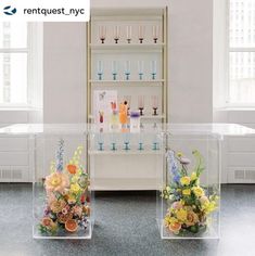 two clear vases filled with flowers on top of a table next to each other