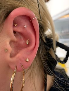 a close up of a person's ear with gold hoops and stars on it